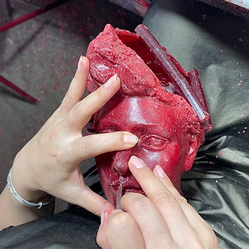 The artisan is meticulously refining the wax model