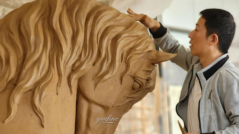Master sculptor working on clay horse head model in studio