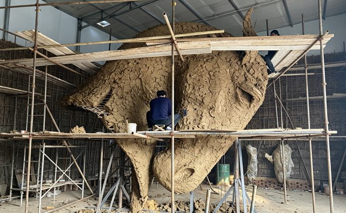 Sculptor reviewing clay model dimensions with client technical drawing