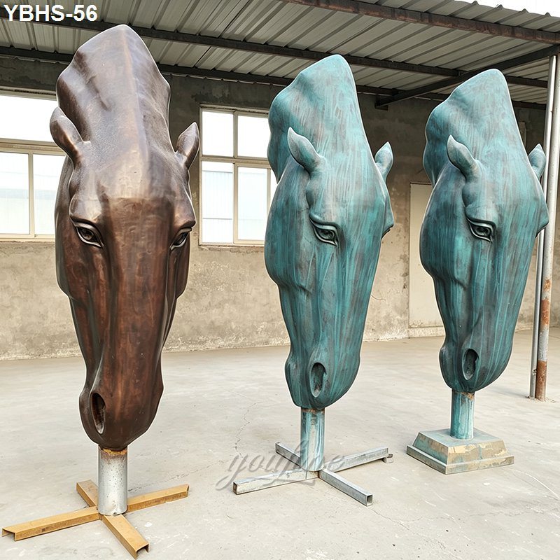 Three large bronze horse head sculptures in contrasting finishes displayed in an outdoor setting for decorative purposes.