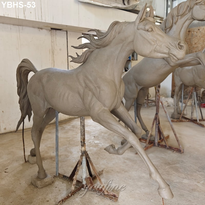 A detailed clay model of a Arabian horse sculpture in a workshop, showcasing dynamic movement and intricate design as part of the bronze casting process.