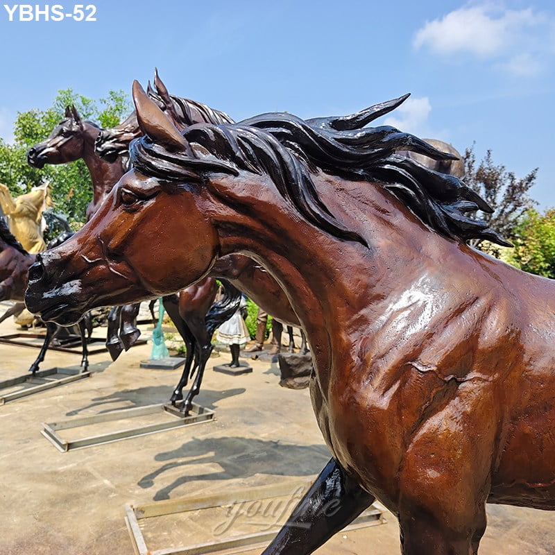 Close-up of a bronze Arabian horse sculpture with flowing mane and realistic detailing, displayed outdoors under a clear blue sky.