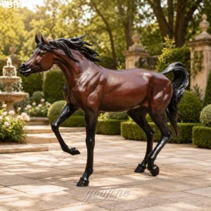 A life-size bronze Arabian horse sculpture with dynamic detailing in a landscaped garden featuring greenery and a classic fountain.