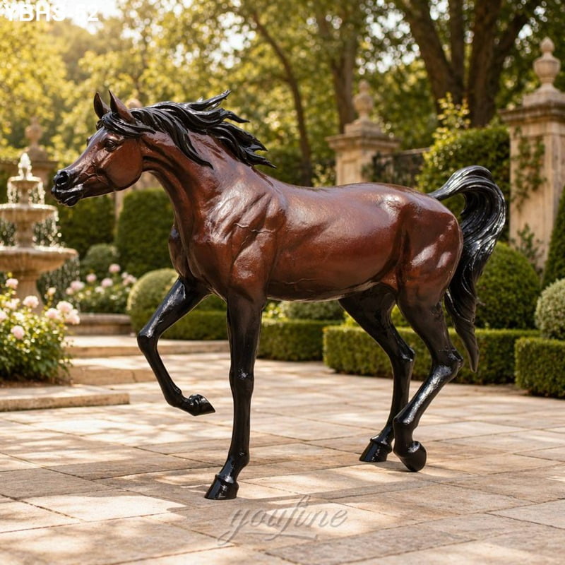 A life-size bronze Arabian horse sculpture with dynamic detailing in a landscaped garden featuring greenery and a classic fountain.