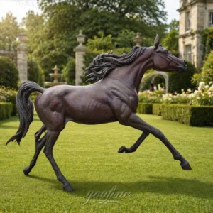 A lifelike bronze Arabian horse sculpture galloping on a manicured lawn surrounded by a formal garden with greenery and a manor in the background.