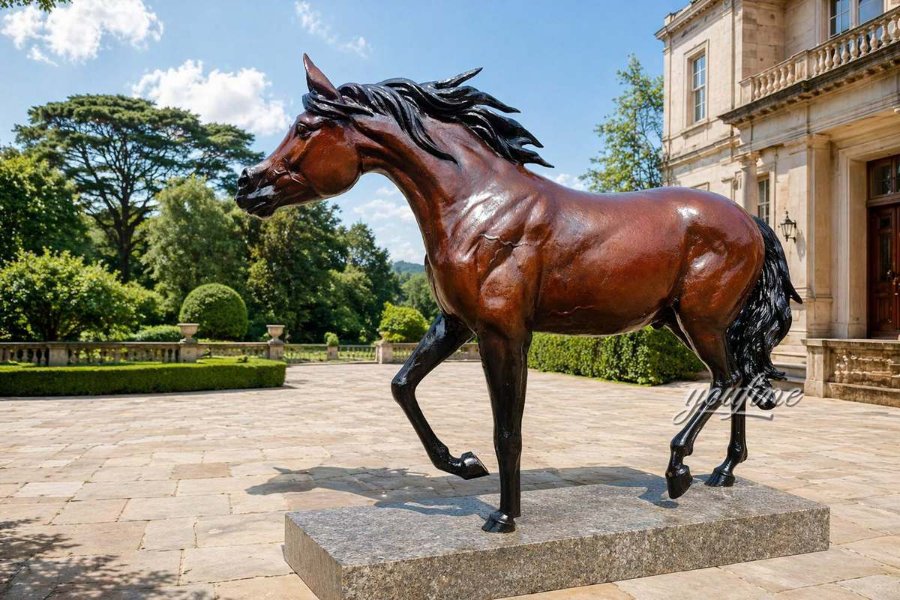 Elegant bronze Arabian horse sculpture with flowing mane in a landscaped courtyard near a grand mansion under a clear blue sky.