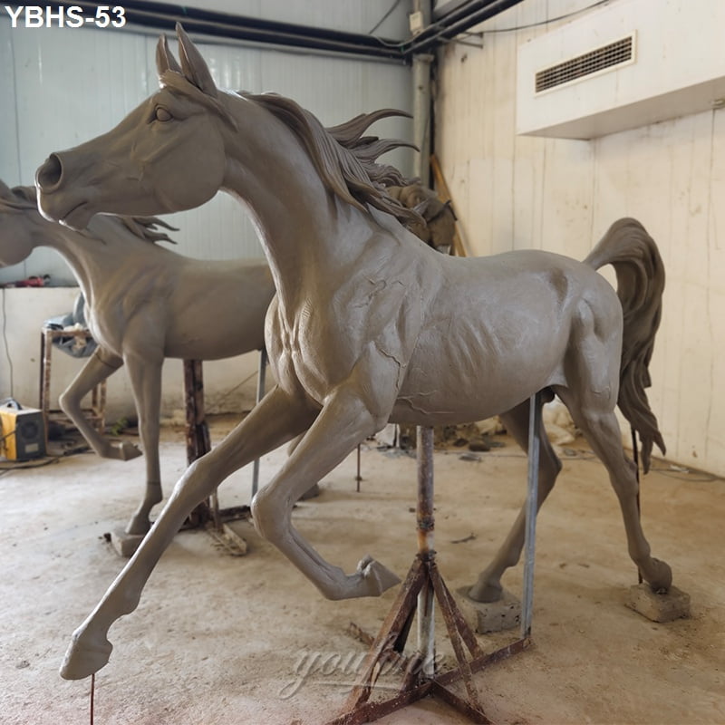 Bronze Arabian horse sculpture in progress, showcasing fine anatomy details and dynamic pose in a workshop setting.