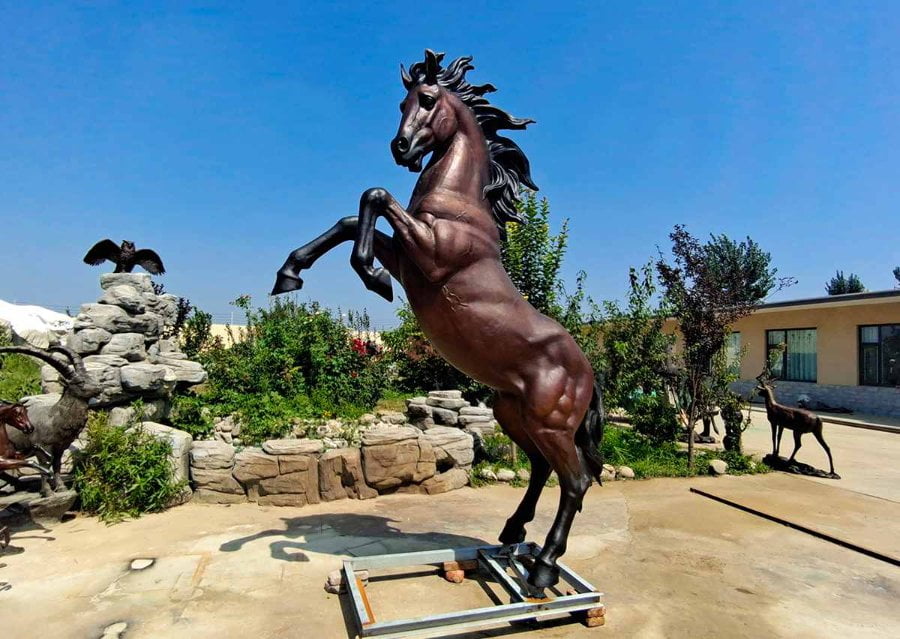 Majestic bronze rearing horse sculpture showcased outdoors with a clear blue sky.