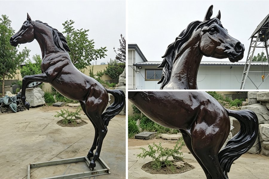 A glossy, dark bronze sculpture of a Arabian horse displayed outdoors on a metal base with trees, shrubs, and a building in the background.