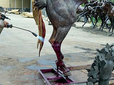 Applying patina to a bronze horse sculpture