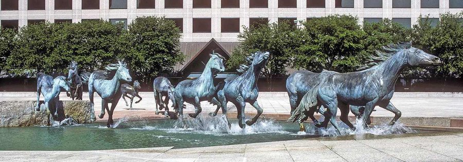 A dynamic The Mustangs of Las Colinas across the water feature