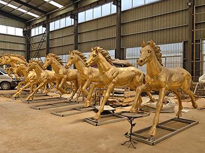A row of polished, unpainted bronze horse sculptures 