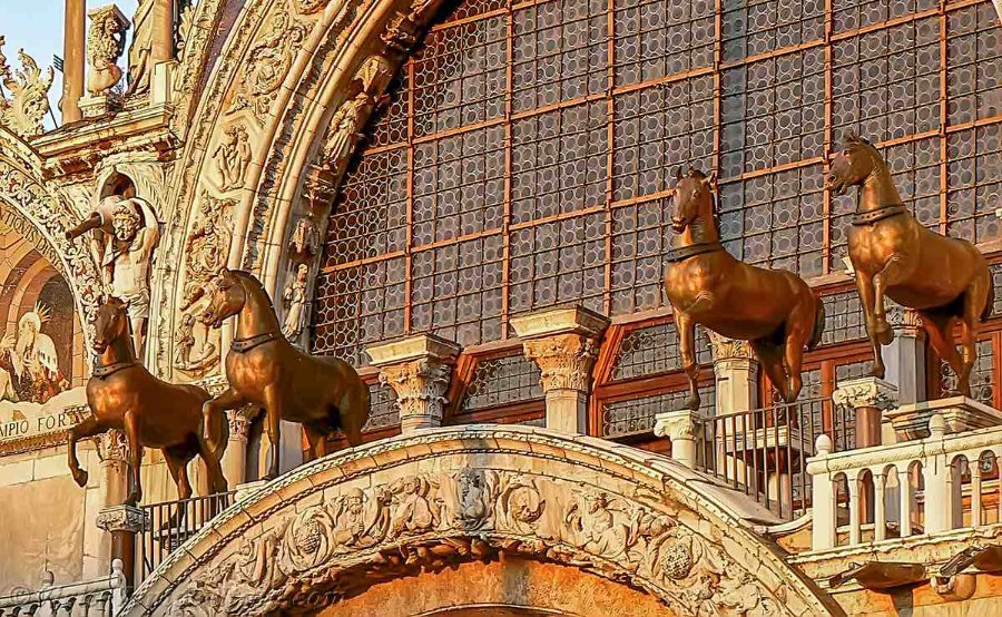 Bronze horse sculptures atop St. Mark's Basilica, showcasing historic architectural and artistic design with intricate details.