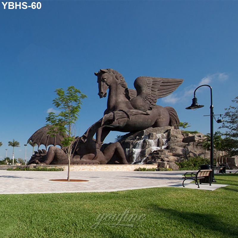 Large bronze Pegasus sculpture in a landscaped park with a fountain, lighting, and seating, under a clear blue sky.