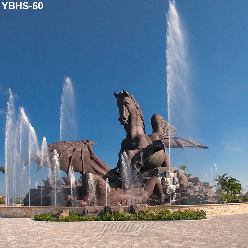 Large bronze winged horse sculpture with dramatic fountain display, surrounded by rocky formations and greenery against a blue sky.