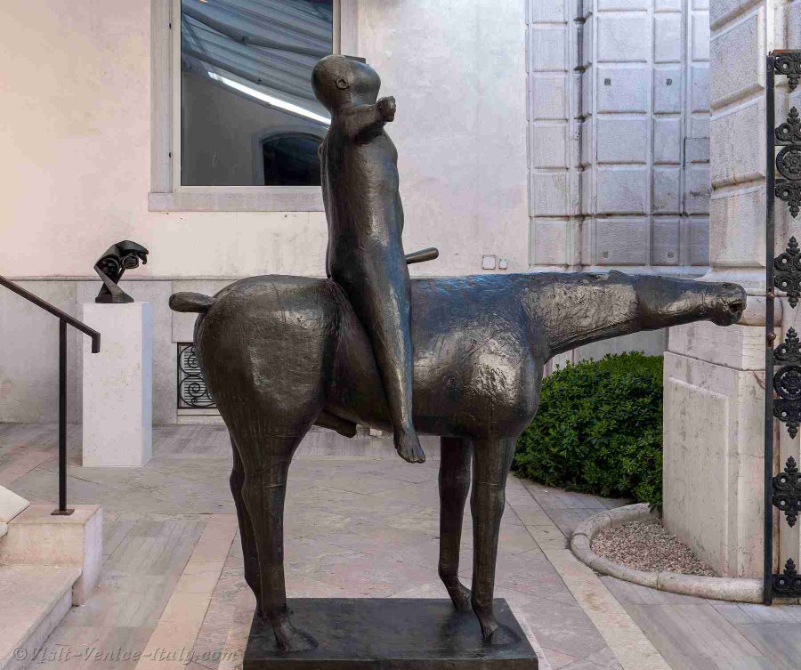 Modern bronze Angel of the City statue, abstract horse with a simplified rider figure on its back in an outdoor courtyard.