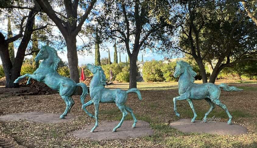 Three bronze horse statues with natural green patina installed in an outdoor garden setting, customer feedback photo from Bronze Horse Sculpture Foundry