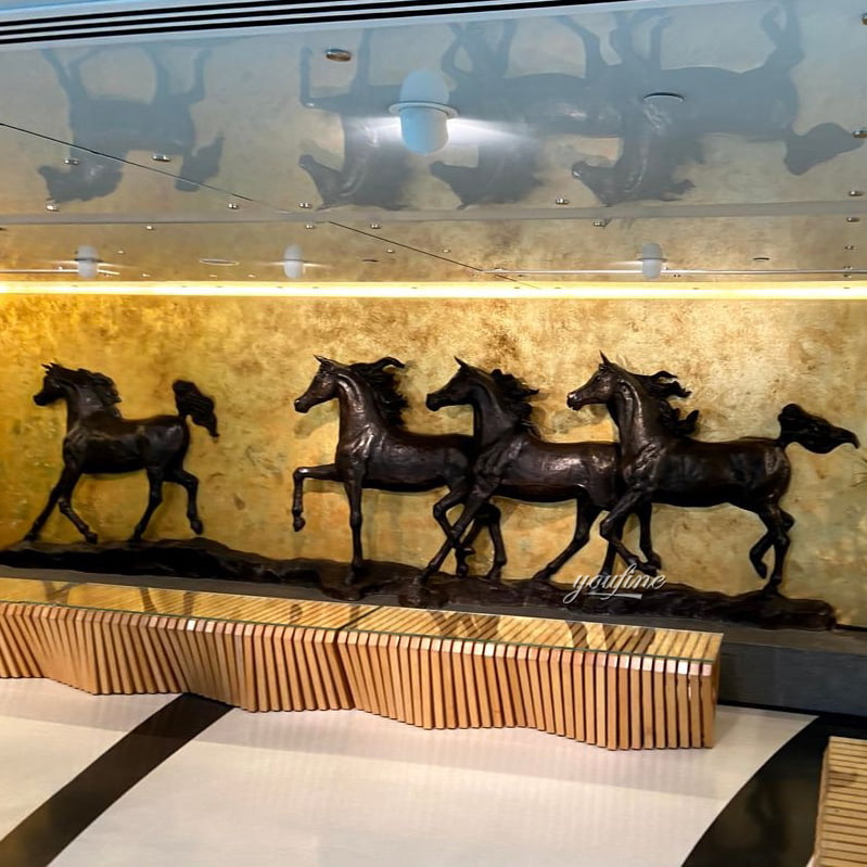 Bronze relief sculpture of five running horses installed beneath a gold frame in a Dubai lobby, custom cast by Bronze Horse Sculpture Foundry