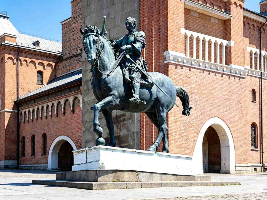 bronze Equestrian statue of Gattamelata with a sword riding a horse, placed on a pedestal near a historic brick building.