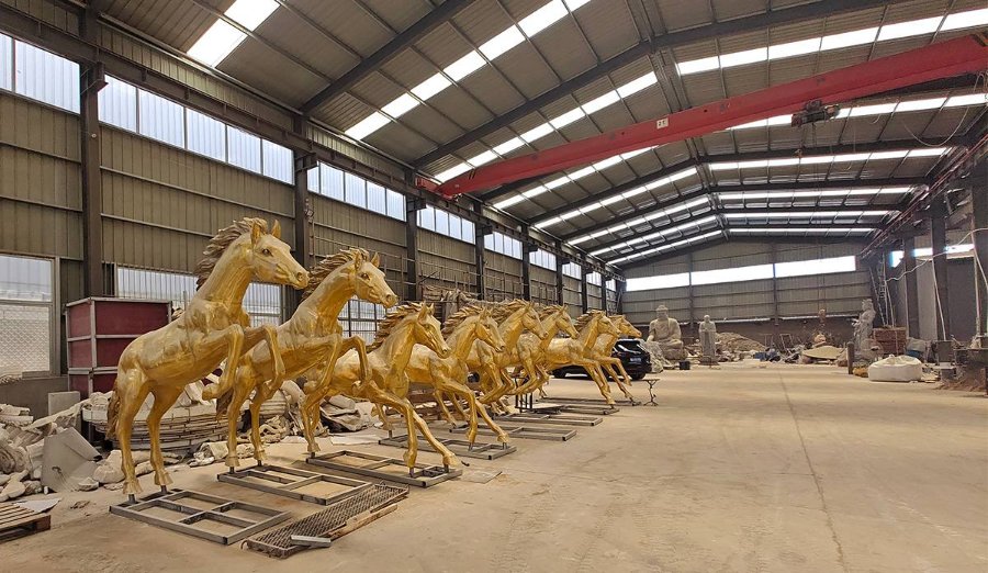 Row of raw cast bronze horse statues in golden unfinished color, lined up in a casting workshop before patina application, at our foundry in Quyang, China
